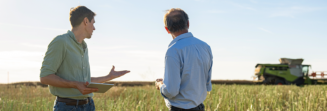 Insurance agent and a farmer in a field of crops with a tractor