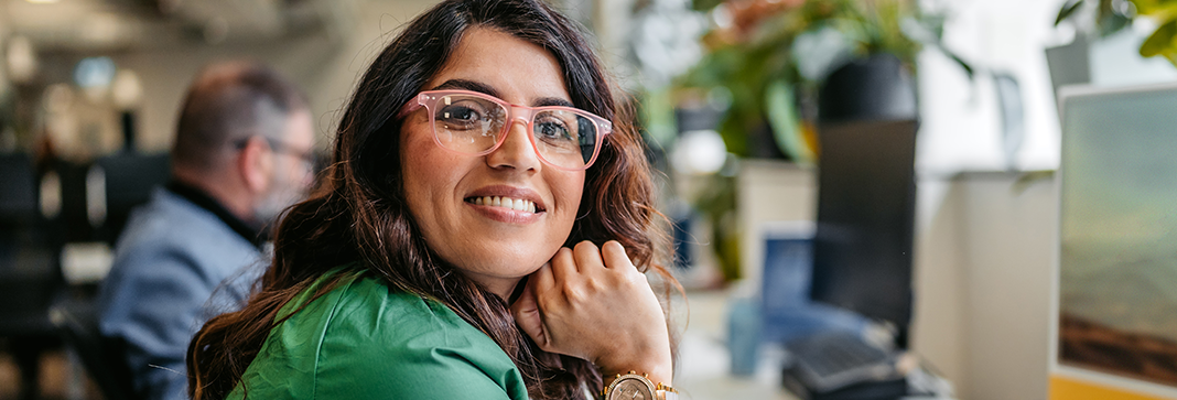A smiling woman at a desktop in an office workspace