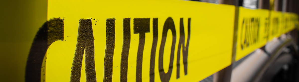 Caution tape over the front window of an office building following a disaster.
