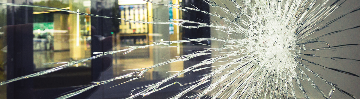 A large crack spreads across a damaged office building window.