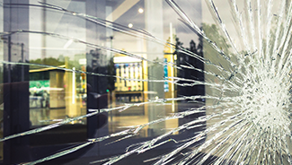 A large crack spreads across a damaged office building window.