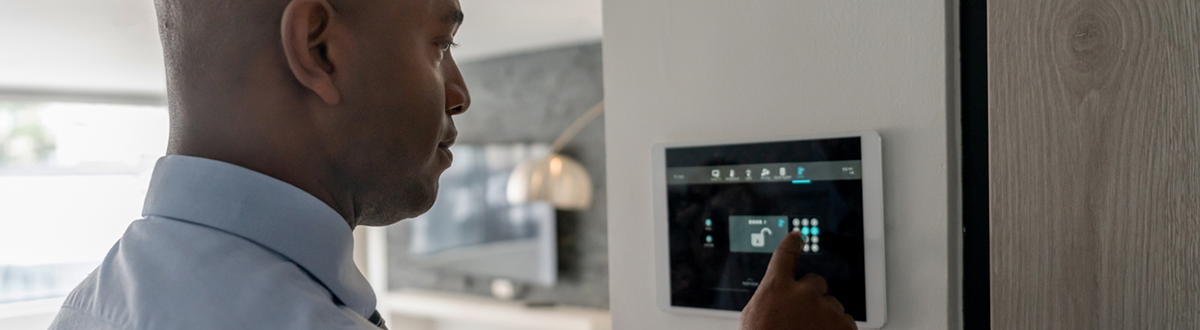 A man in a blue shirt ensures the doors in his  house are locked using a home security system.