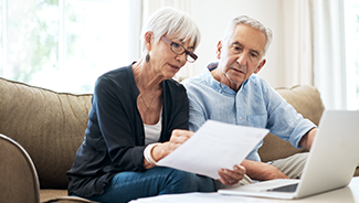 A senior couple going through their home insurance policy while sitting on the sofa at home.