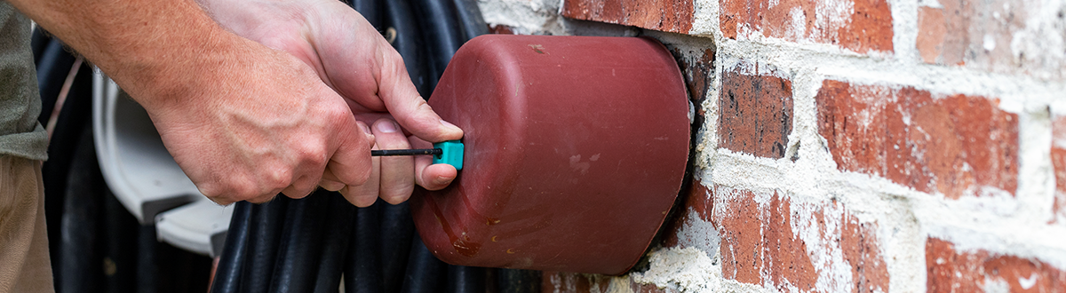 Hand installs outdoor faucet cover to protect plumbing from freezing in the winter