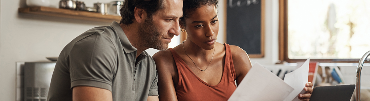 Cropped shot of a couple using their laptop and going through paperwork at home