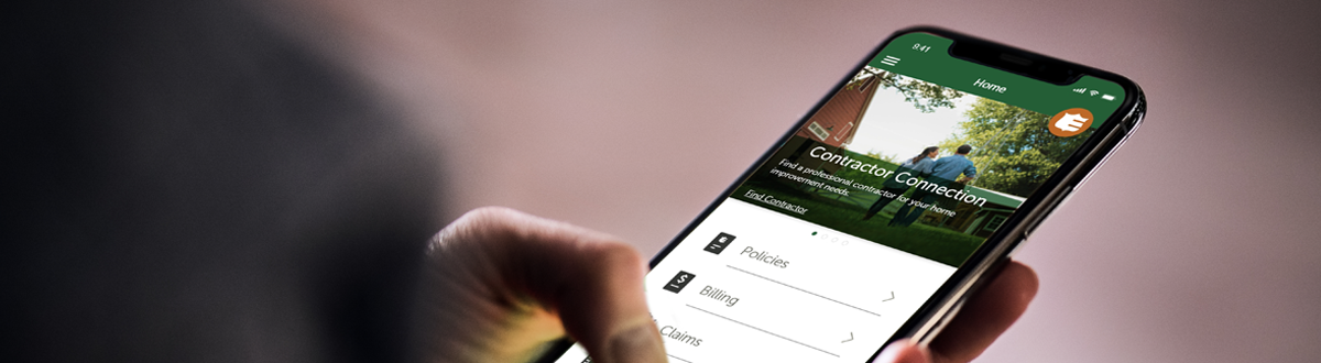 A hand is holding a cell phone and using the Mutual of Enumclaw mobile app.