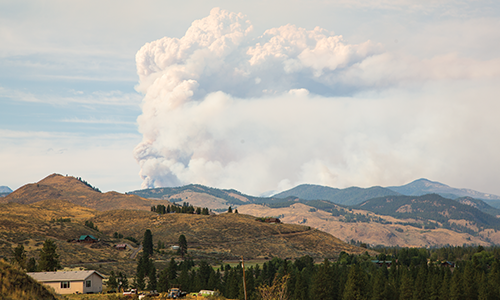 Wildfire smoke over a mountain range behind a home